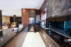 Cozinha gourmet do salão de festas com bancada de granito escuro, armários amadeirados e geladeira inox — Summer Park Residence - Fase 2 em Vargem do Bom Jesus, Florianópolis