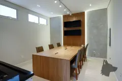 Sala de reuniões com mesa de madeira, 8 cadeiras, painel ripado e iluminação de trilho — Summer Park Residence - Fase 2 em Vargem do Bom Jesus, Florianópolis