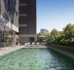 Piscina linear ao lado do edifício com espreguiçadeiras, guarda-sol e jardim — Torres do Porto em Estreito, Florianópolis