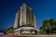 Fachada frontal do edifício à noite com lojas no térreo iluminadas — Unity em Estreito, Florianópolis