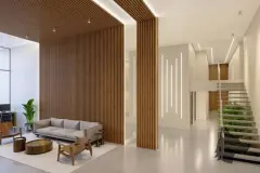 Hall de entrada com painel de ripas de madeira, sofá, escada com jardim vertical e iluminação LED — Unity em Estreito, Florianópolis
