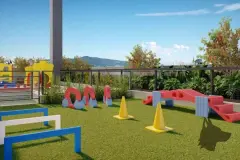 Área kids externa com gramado, obstáculos e equipamentos de lazer coloridos — Unity em Estreito, Florianópolis