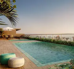 Piscina do rooftop com deck, espreguiçadeiras, guarda-sol e vista para a baía ao pôr do sol — Unity em Estreito, Florianópolis