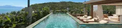 Piscina de borda com deck de madeira, espreguiçadeiras, plantas tropicais e vista para morros e mar — Upside Beach em Ponta das Canas, Florianópolis