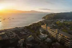 Painel de TV em ripas de madeira bege com rack de madeira e cortina branca — Upside Beach em Ponta das Canas, Florianópolis