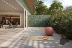 Área externa de yoga e pilates com tapete, bola de pilates, jardim tropical e academia ao fundo — Upside Beach em Ponta das Canas, Florianópolis