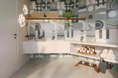 Pet spa com bancada de mármore, torneira, toalhas, produtos e azulejo estampado com letreiro neon de patinhas — Upside Beach em Ponta das Canas, Florianópolis