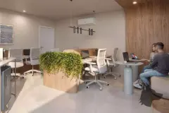Coworking com mesas, cadeiras ergonômicas, notebook, plantas e parede revestida de madeira — Upside Beach em Ponta das Canas, Florianópolis