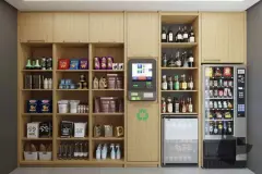 Mini mercado com prateleiras de madeira clara com produtos, totem de pagamento e adega de vinhos — Viel Spaβ em Ingleses, Florianópolis