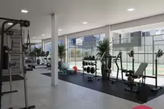 Academia equipada com rack de halteres, barras paralelas, esteiras e saco de boxe, vista para a quadra — Viel Spaβ em Ingleses, Florianópolis