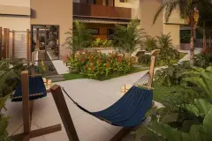 Jardim interno com redes azuis, flores vermelhas e acesso à academia ao fundo — Villa Maggiore em João Paulo, Florianópolis