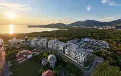 Vista aérea vertical ao pôr do sol com complexo residencial, lagoa e morros ao fundo — Villa Maggiore em João Paulo, Florianópolis