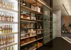 Interior do minimercado com cervejeira iluminada à esquerda, prateleiras de alimentos ao centro e parede de armários à direita — Viva Balneário Estreito em Balneário, Florianópolis