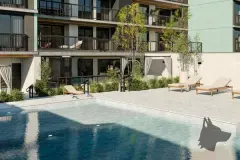 Piscina com espreguiçadeiras, cabanas com cortinas e vegetação, fachada do edifício refletida na água — Viva Balneário Estreito em Balneário, Florianópolis