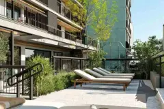 Deck da piscina com fileira de espreguiçadeiras encostadas ao edifício, árvores e jardins ao redor — Viva Balneário Estreito em Balneário, Florianópolis