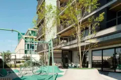 Playground externo com balanços, cúpula geodésica verde, morro de plástico e edifício com varandas ao fundo — Viva Balneário Estreito em Balneário, Florianópolis