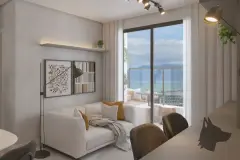 Sala de estar com sofá branco, almofadas amarelas, quadros na parede e porta de vidro para varanda com vista para o mar — VYU One em Coqueiros, Florianópolis