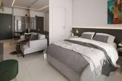 Studio com cama de casal com cabeceira dark, sofá cinza, mesa de jantar e cozinha integrada — VYU One em Coqueiros, Florianópolis