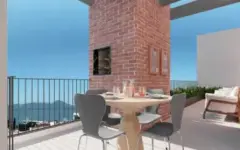 Varanda gourmet com churrasqueira embutida em pilar de tijolo, mesa redonda e vista para o mar — VYU Pulse em Coqueiros, Florianópolis