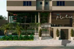 Entrada do edifício VYU Pulse com jardim tropical, fachada de vidro e letreiro do empreendimento — VYU Pulse em Coqueiros, Florianópolis