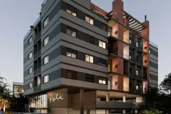 Fachada diagonal do edifício VYU Pulse ao entardecer com iluminação interna nas janelas — VYU Pulse em Coqueiros, Florianópolis