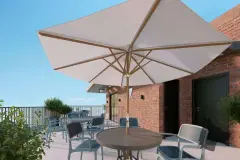 Terraço com mesa redonda, cadeiras e guarda-sol grande de madeira junto a parede de tijolinho — VYU Pulse em Coqueiros, Florianópolis