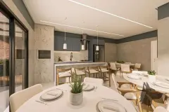 Sala de jantar com mesas redondas brancas, cozinha azul com ilha e varanda ao fundo à noite — VYU Pulse em Coqueiros, Florianópolis
