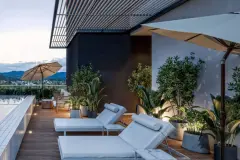 Terraço de cobertura com duas espreguiçadeiras, guarda-sóis, vasos e vista para as montanhas ao entardecer — Yuná Blue View em Campeche, Florianópolis